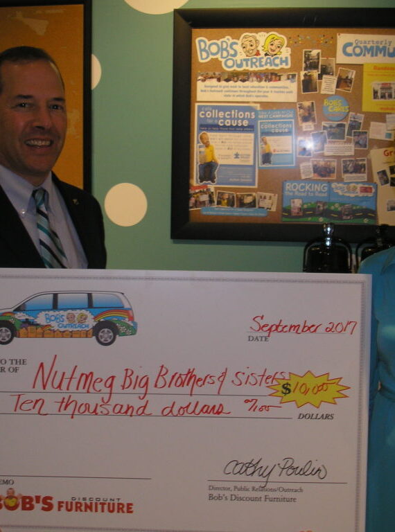 Two people holding a large donation check.